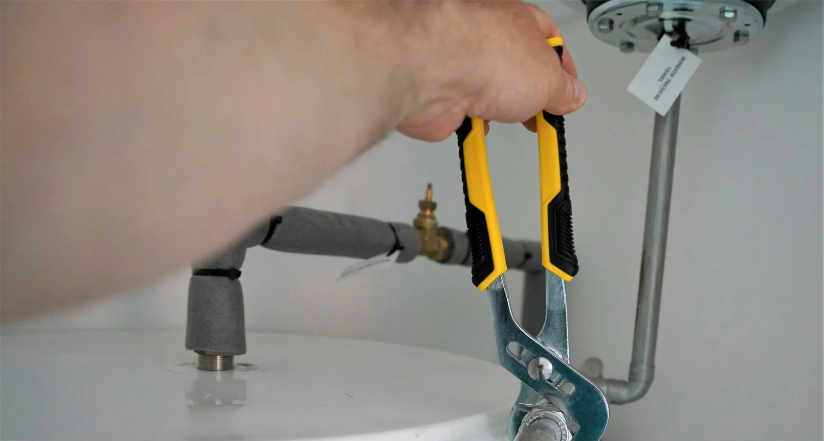 Mani di tecnico al lavoro sui raccordi idraulici di una caldaia